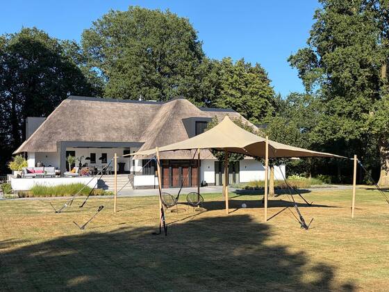 Stretchtent in een particuliere tuin bij een rieten landhuis